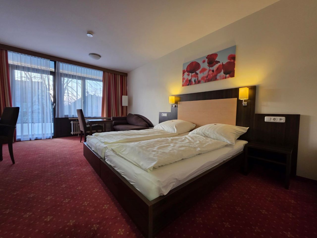 Helles Doppelzimmer Superior im Hotel SONNE-POST mit Doppelbett, Balkonzugang und warmer Beleuchtung